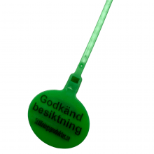 Nærbillede af grønt inspektionsmærkat, der tydeligt viser mærkningen og den slidstærke plastkonstruktion.