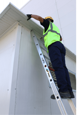 Miljöbild med arbetande person, lutad mot byggnad
