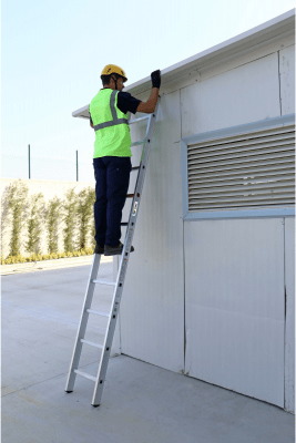 Miljöbild med arbetande person, lutad mot byggnad