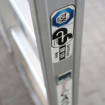 Klistermärken med certifikat på utsidan av en grå takstege