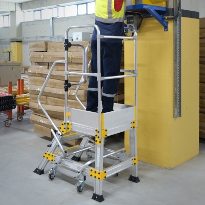 Miljöbild där en man med svarta arbetskläder och reflexväst står på en plattformstrappa