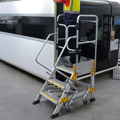 Miljöbild där en man med svarta arbetskläder och reflexväst står på en plattformstrappa