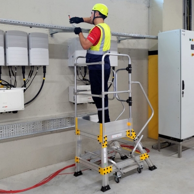 Miljöbild där en man med svarta arbetskläder och reflexväst står på en plattformstrappa