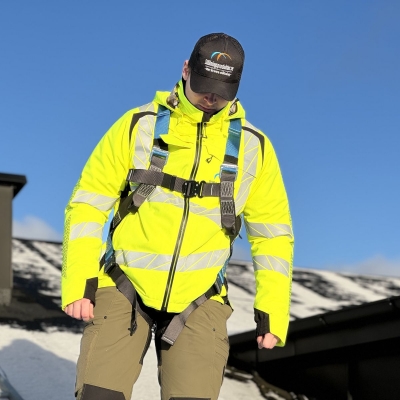 blå och svart fallskyddssele på man i varseljacka på tak