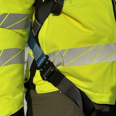 blå och svart fallskyddssele på man i varseljacka på tak närbild snabbfäste