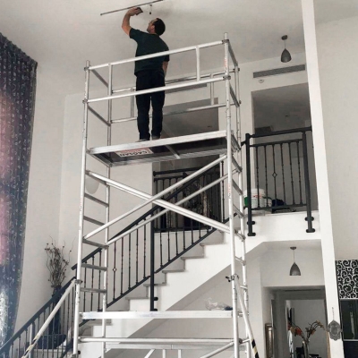Hantverkarställning smal 6m i aluminium med man i varsel arbetades på översta plattformen inomhus