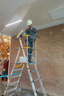 trppstegen står uppställd på arbetsplats med person på plattform som jobbar