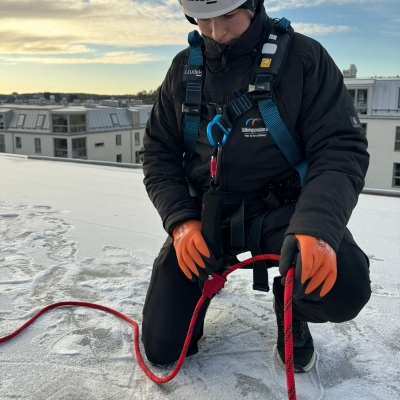 Röd förankringslina fäst i bröstet på sele